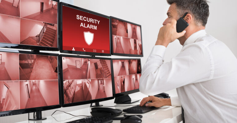 Male,Operator,Using,Walkie-talkie,While,Monitoring,Multiple,Cctv,Footage